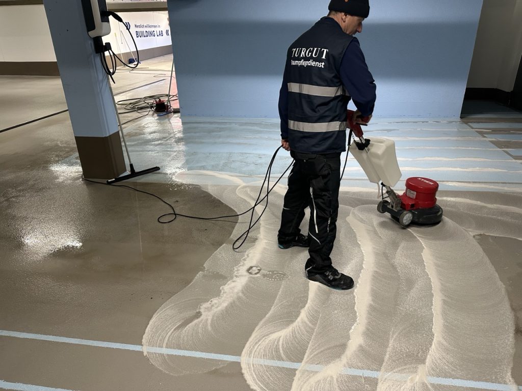 Grundreinigung einer Tiefgarage mit Reinigungsmaschine durch einen Mitarbeiter der Turgut Gebäudereinigung
